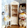 A handcrafted miniature mushroom tableware set displayed next to a dollhouse cabinet and a plush toy.