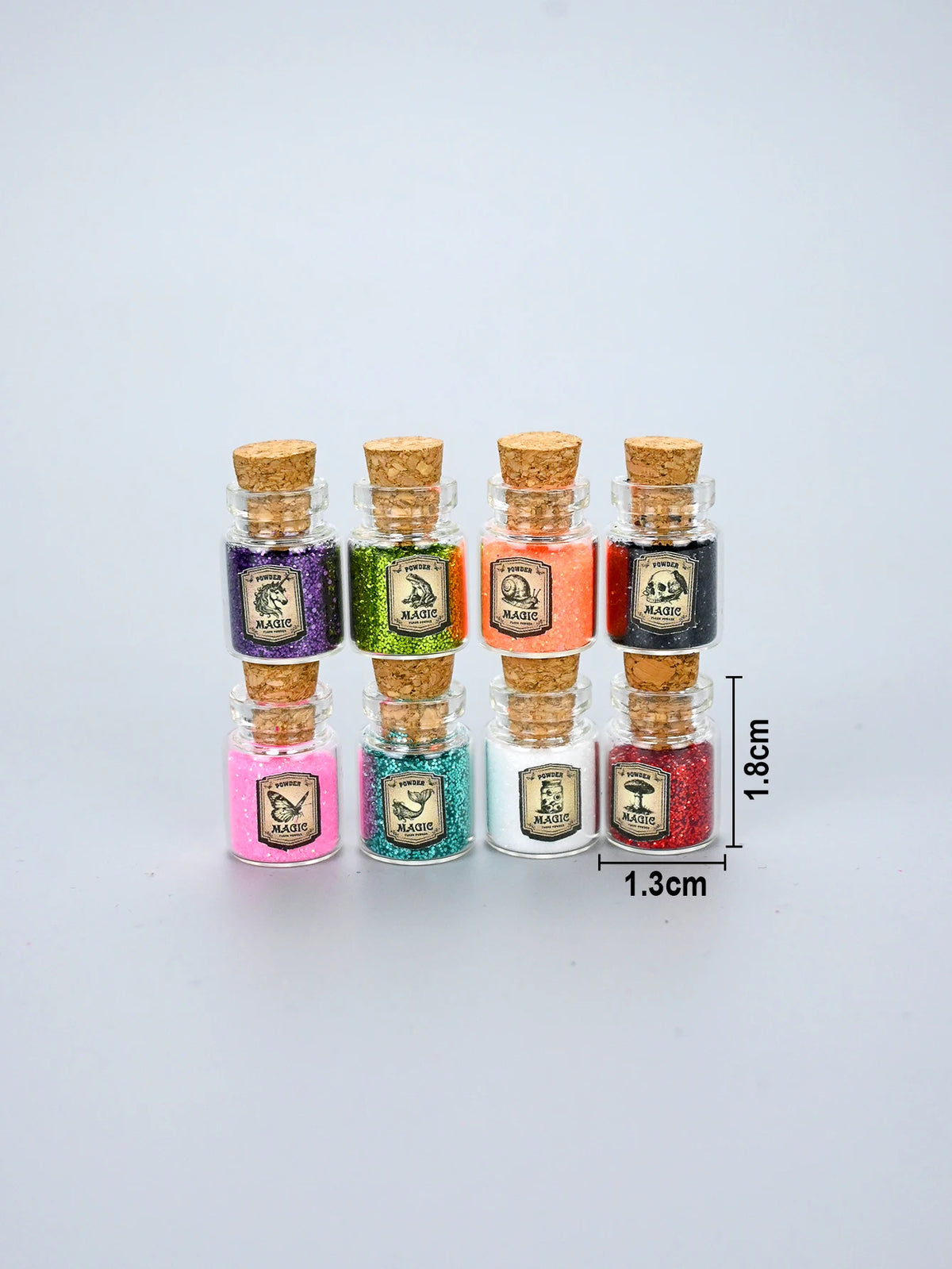 A collection of eight glass jars filled with glitter powder in various colors and labeled Magic