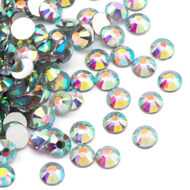 A collection of round flatback resin rhinestones in various iridescent colors and shades scattered on a white background.