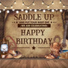 A rustic wooden backdrop featuring a saddle, boots, and guitar with text wishing a happy birthday.
