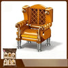 A detailed miniature vintage armchair model in orange-yellow wood with brass accents.