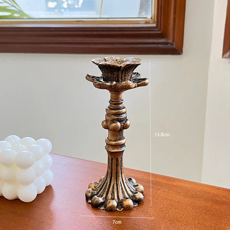 A vintage resin wall sconce candle holder with a bronze finish, displayed on a wooden surface.