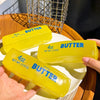 Trois jouets anti-stress en beurre jaune sont présentés sur une assiette blanche.