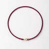 A handmade red string bracelet with a gold plated clasp, shown against a white background.