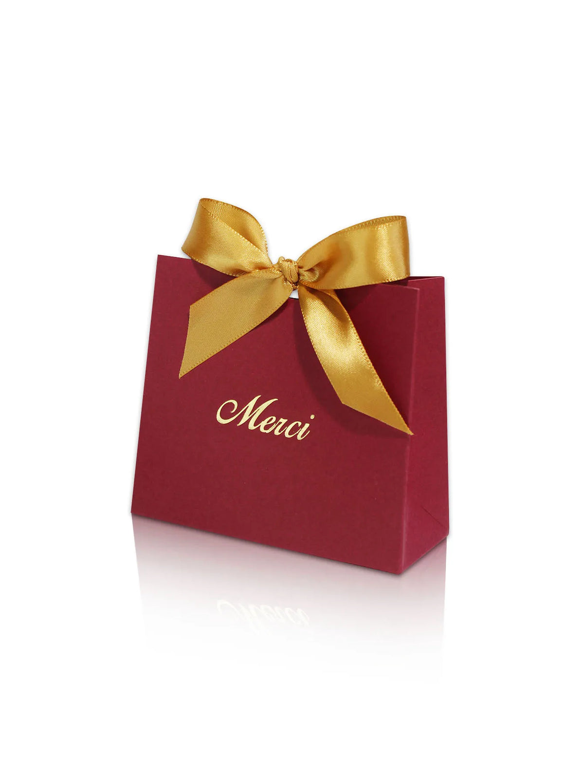 A red paperboard thank you gift bag tied with a gold ribbon, featuring the word Merci printed on it.