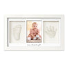 A white framed print featuring a baby's handprint and footprint on a light background.