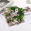 White artificial daisy flower bundles with green foliage displayed on a piece of paper.