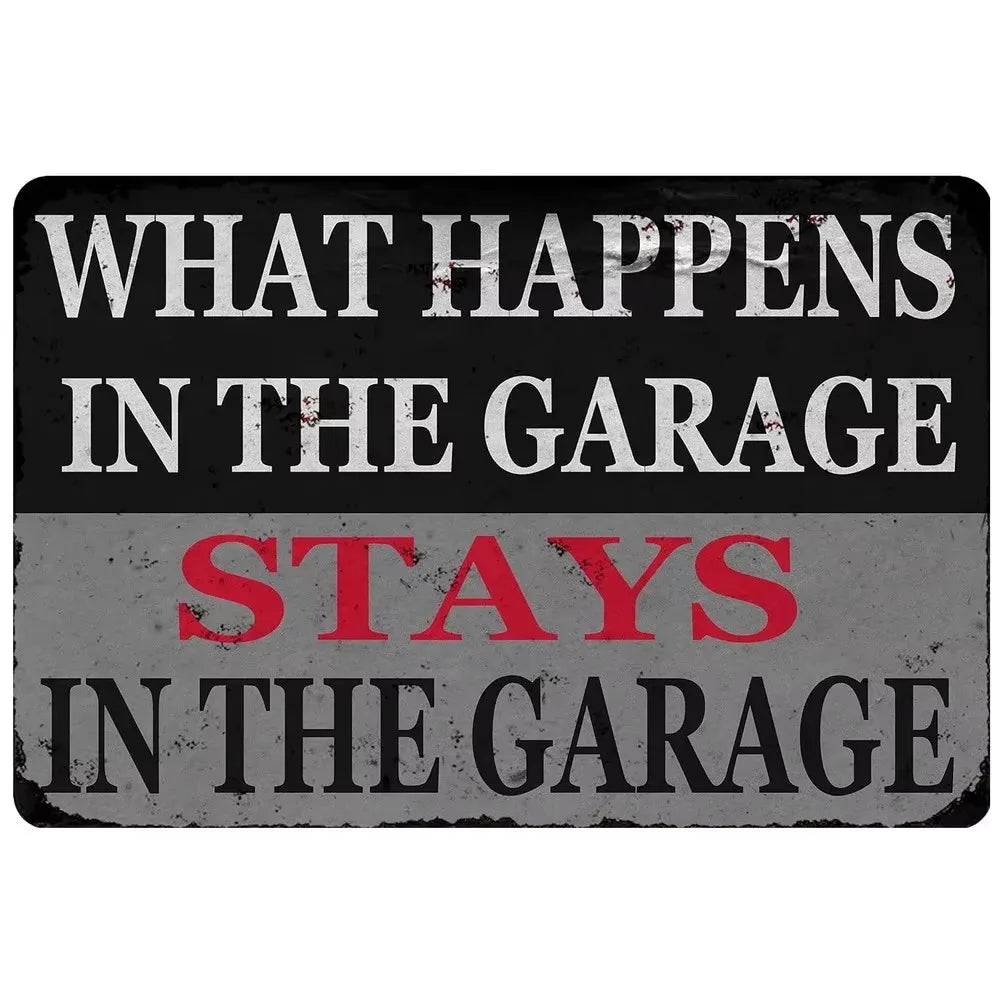 A distressed metal tin sign with white text on a dark background that reads What happens in the garage stays in the garage