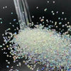 A pile of multicolor glass micro beads scattered on a dark surface with a glass dropper above.