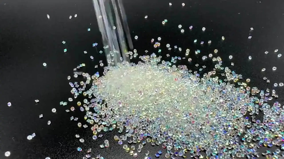A pile of multicolor glass micro beads scattered on a dark surface with a glass dropper above.