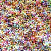A close-up view of a large pile of colorful pastel foam beads in various shades of pink, blue, yellow, and green.