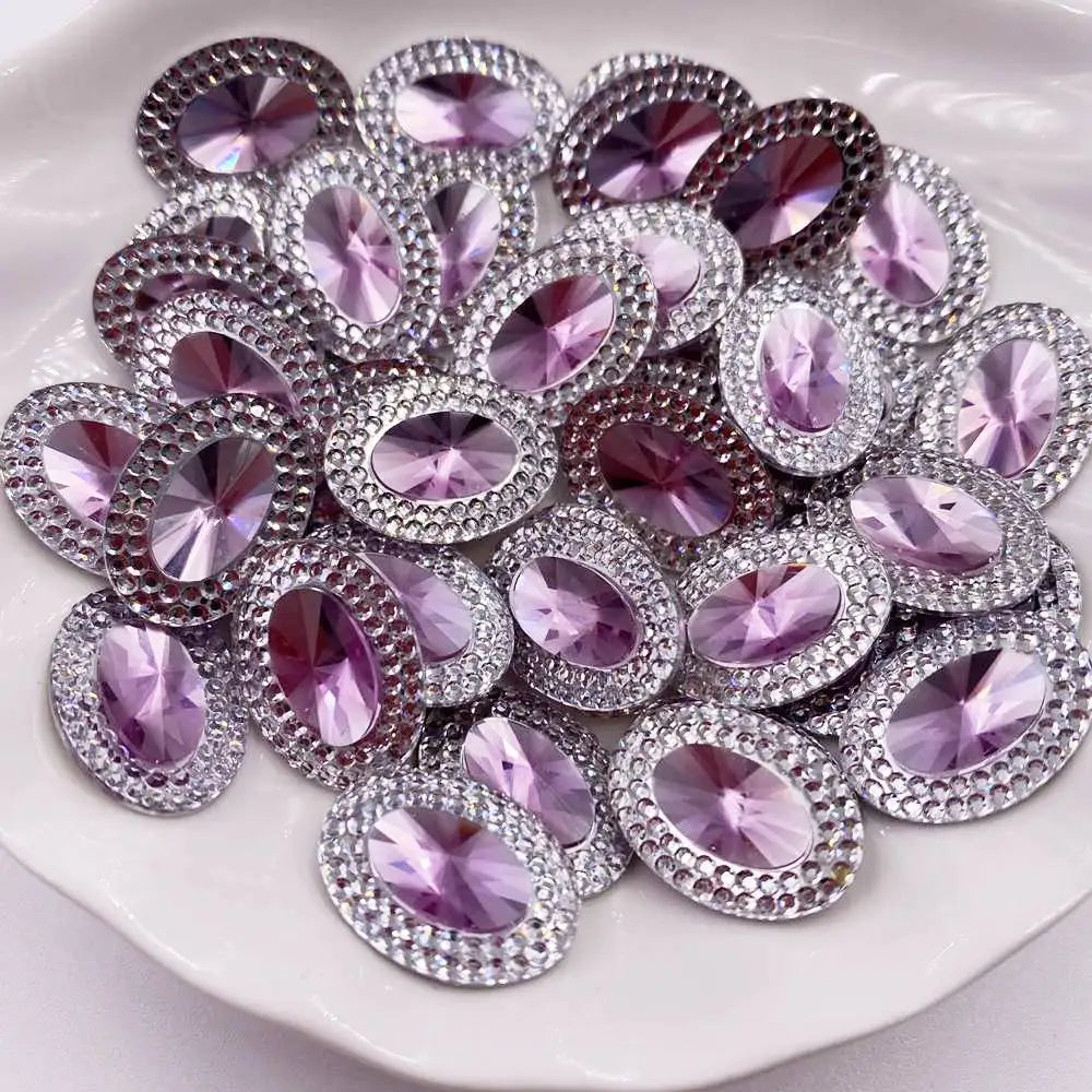A pile of purple and pink gemstone flatback rhinestones for crafting arranged on a white surface.