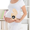 A pregnant woman holds a wooden ultrasound photo frame showing an embryo and a baby silhouette.