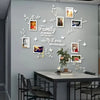 A gray wall decorated with a white floral vine design and several framed photos, featuring the text Family is where life be g
