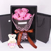Un ramo de rosas rosadas y un oso de peluche en una caja gris oscuro hecho a mano.