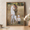 A framed photo of a mother and child standing in a field, with the child wearing a white hat.