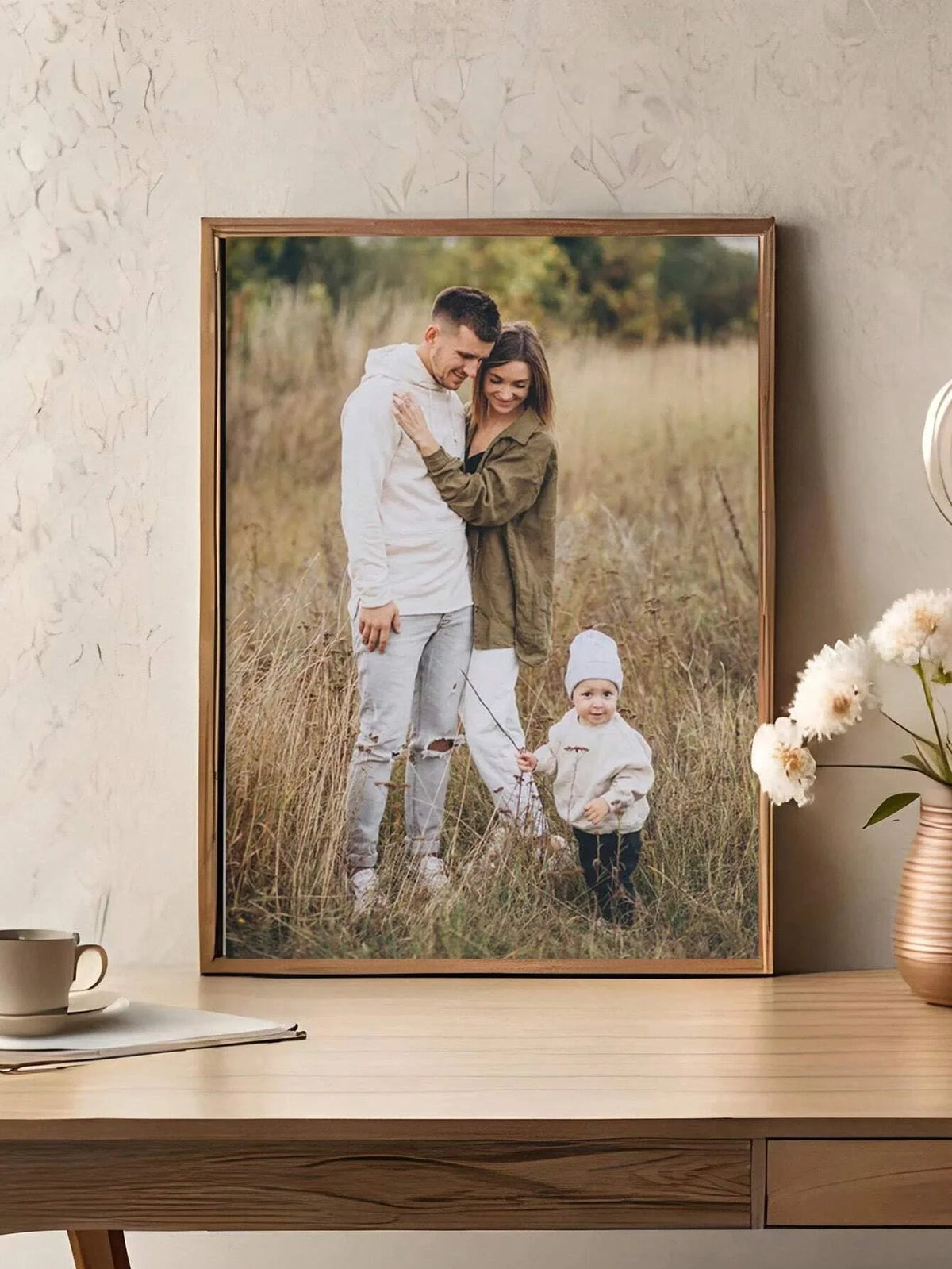 A framed photo of a mother and child standing in a field, with the child wearing a white hat.