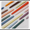 A collection of long tapered candles in various gradient colors, including orange, pink, purple, and green tones.