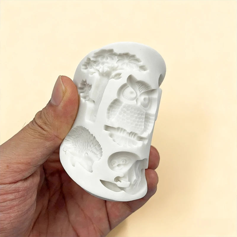 A hand holds a white silicone mold shaped like various Halloween creatures for chocolate and candy