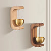 A magnetic wooden door bell with a brass wind chime is mounted on a light-colored wall.