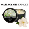 A black jar of Jasmine massage candle with a lit wick and a white jasmine flower nearby.