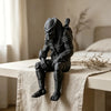 A dark black Interstellar Hunter figurine sculpture sitting on a light-colored cloth next to a window.