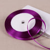A purple satin ribbon spool is shown on a white card against a beige background.