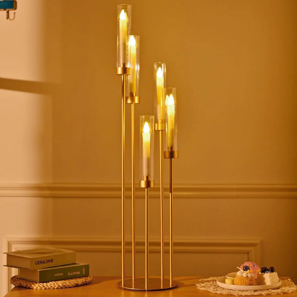 Un ensemble de cinq photophores LED dorés posés sur une surface en bois avec des éléments décoratifs.
