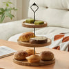 A wooden 3-tier cupcake stand with detachable layers displaying baked goods on a light surface.