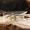 Handcrafted brass rooster figurine with intricate details resting on a wooden surface.