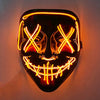 A glow-in-the-dark LED purge mask with glowing orange lines forming an 'X' pattern and a toothy grin.
