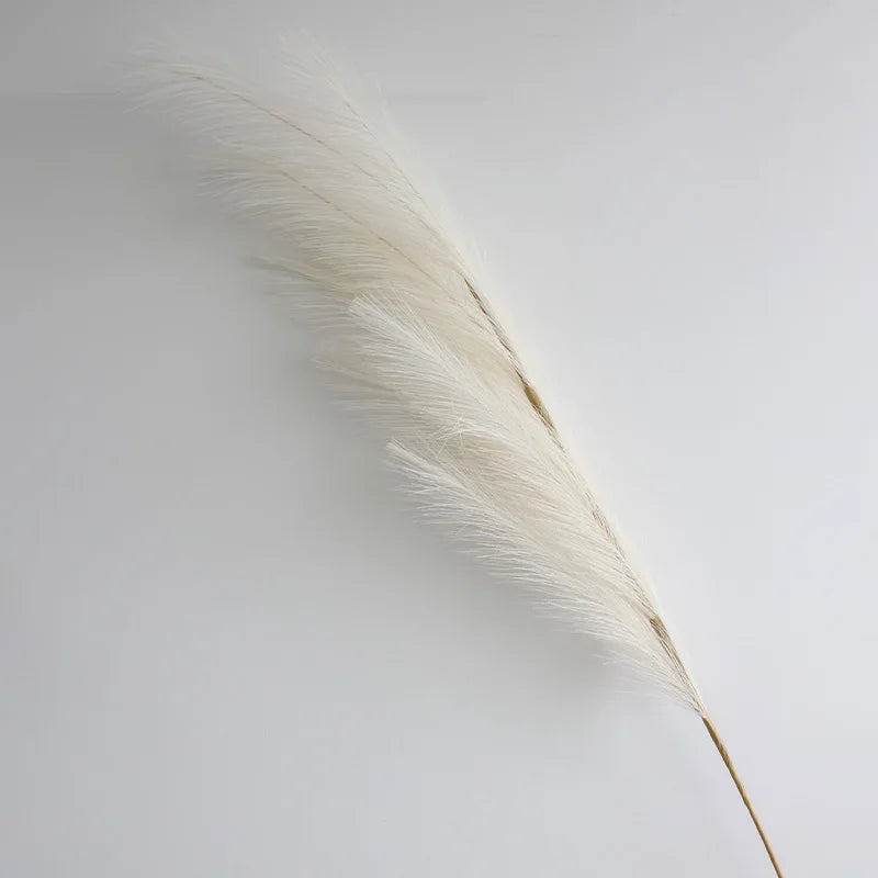 A long, feathery, beige artificial pampas grass stem used for boho home decor.
