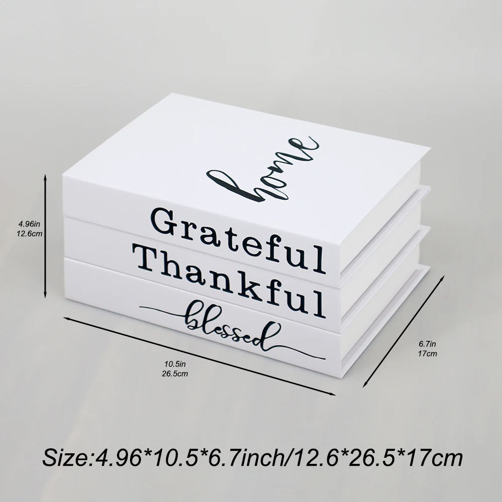 A stack of three modern decorative fake books in white featuring the words grateful thankful and blessed