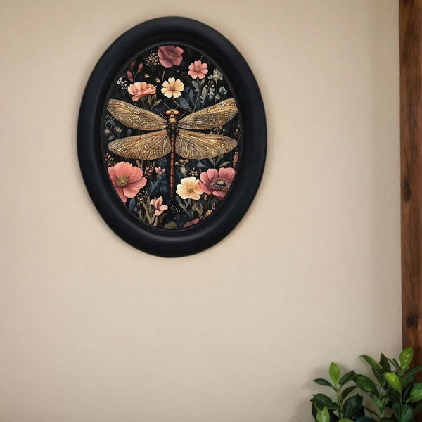 Oval framed artwork featuring a detailed illustration of a dragonfly among various pink and yellow flowers.
