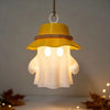 A yellow camping ghost night light hangs, featuring a glowing white face and a brimmed hat.