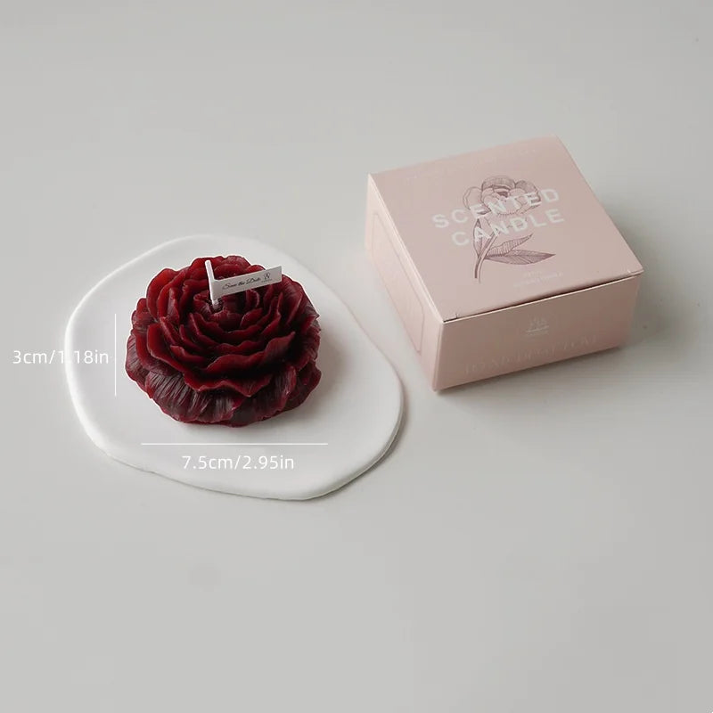A handcrafted rose-shaped scented candle in a pink box and on a white plate.