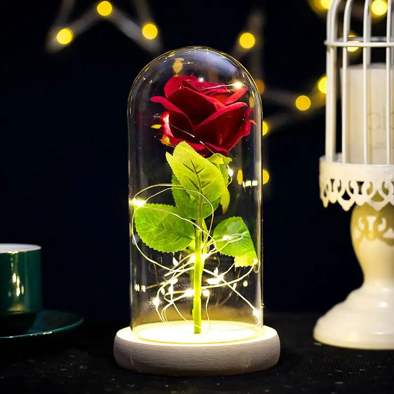 A glass jar containing a red rose and green leaves illuminated by a bright LED light.