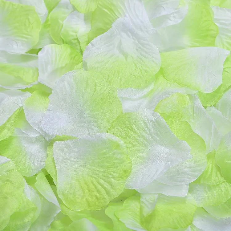 Light green artificial silk rose petals scattered on a white background.