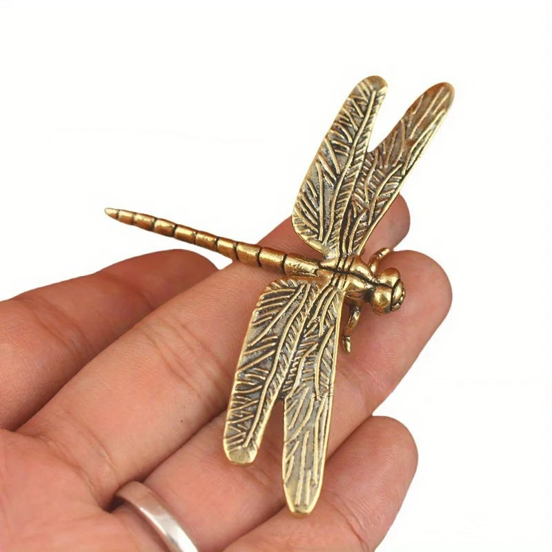 Vintage brass dragonfly desk decor resting on a person's hand