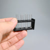 A hand holds a black miniature laboratory set with five clear glass tubes for dollhouse or photography