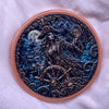 A round copper coin design featuring a dark figure with a crown, surrounded by sea elements and a crescent moon.