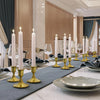 Vintage iron candlestick holders with white candles arranged on a table setting.
