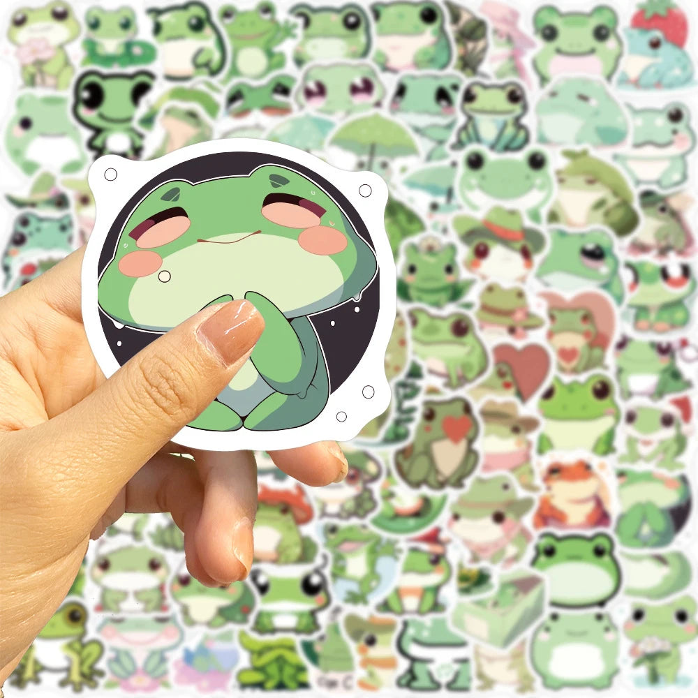 Une main tient une étiquette blanche avec le visage d'une grenouille verte esthétique sur fond noir, entourée de petites gren