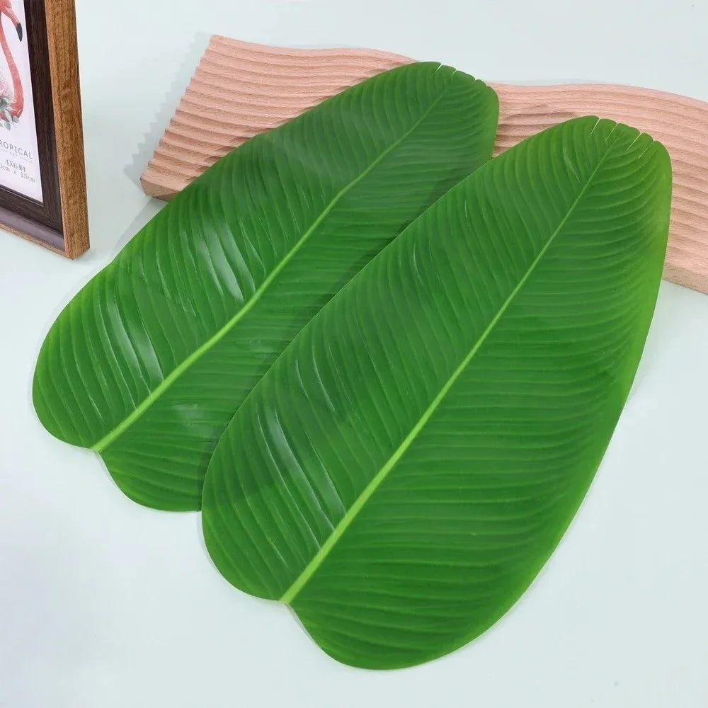 A set of five green tropical banana leaf coasters resting on a light wooden surface.