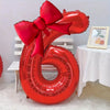 A large red foil number balloon shaped like the number 6, tied with a matching red bow.