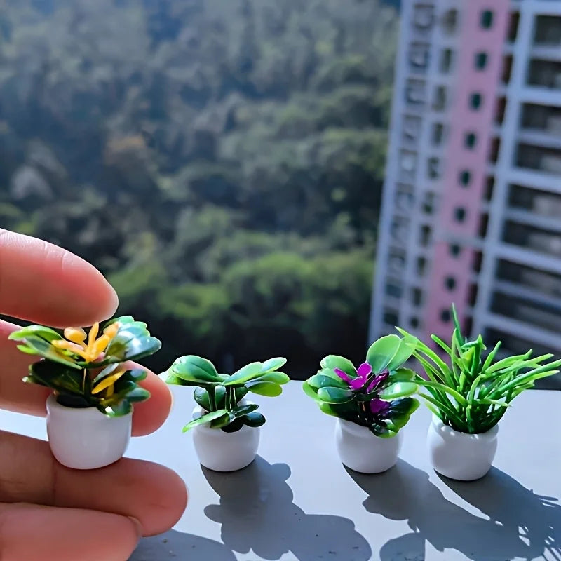 A hand holds a set of miniature potted plants with green and yellow leaves on a gray surface.