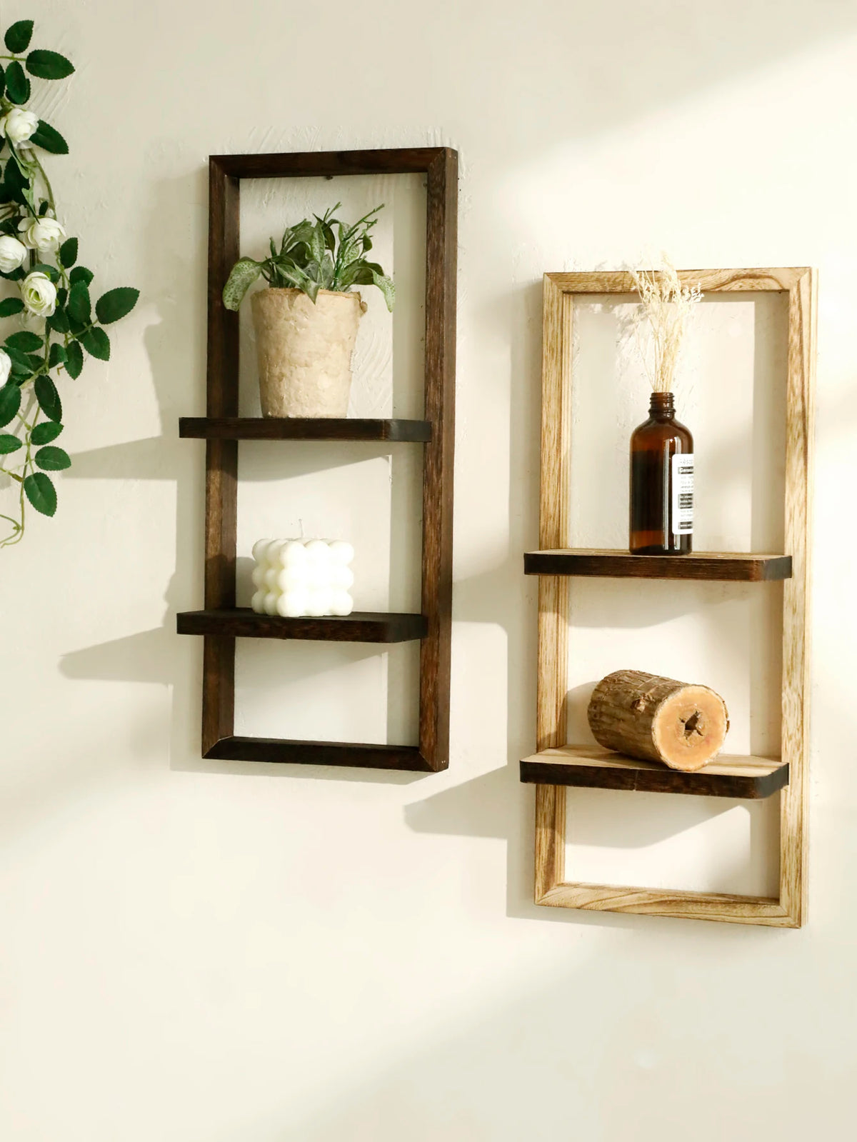 A rustic wooden floating shelf with two tiers displaying a potted plant and a candle.