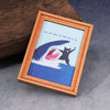 A framed print featuring a silhouette of a cat leaping over water against a blue background.