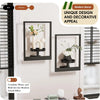 Modern black metal wall planters displaying greenery and white flowers on a light gray wall.