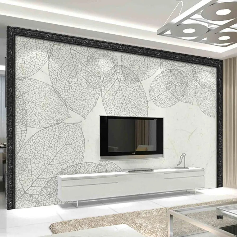 A modern interior featuring a large wall panel with a white leaf pattern and a black frame, displaying a mounted television.